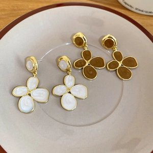 Gros plan de boucles d'oreilles en émail blanc et caramel avec monture en métal doré