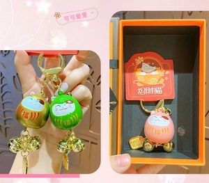 Detailed view of colorful Maneki Neko bell charms in orange gift box packaging