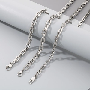 Detailed shot of three silver square link chains with lobster clasps on a grey stand