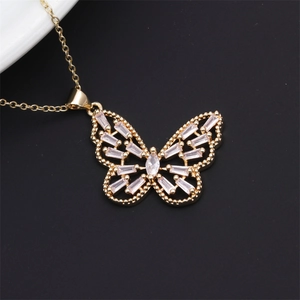 Close-up of gold butterfly pendant with cubic zirconia on a white plate edge
