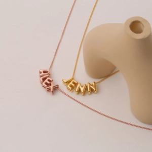 Dettaglio di collane personalizzate in oro rosa e oro con i nomi Alex e Jenn in evidenza