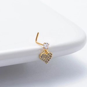 Détail d'un piercing de nez en forme de L doré avec pendentif cœur en cristal scintillant
