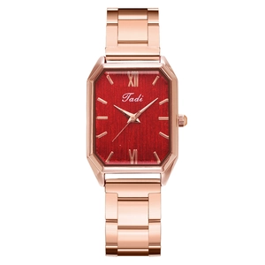 Detail of rose gold rectangular watch with red brushed dial and Roman numerals
