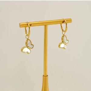 Detail of golden butterfly earrings with white mother-of-pearl wings on a jewelry stand
