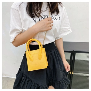 Yellow mini jelly bag with croc texture and gold chain strap held by a model