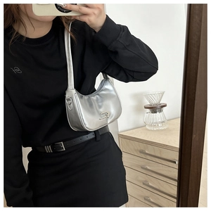 Mirror selfie showing the metallic silver crescent underarm bag with black outfit