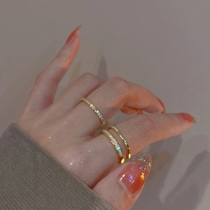 Detail of double-layer gold plated ring with zircons on model's hand in soft focus