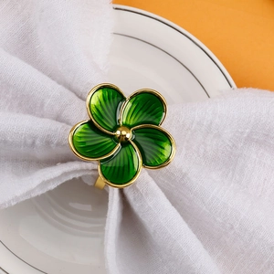 Elegant green flower napkin ring with gold edges on white linen for banquet table setting