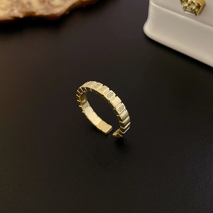 Detail of gold plated geometric ring with cubic zirconia on black leather background
