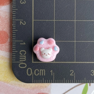 Mini pink cat paw resin charm with bear pattern and colorful hearts on a measurement mat