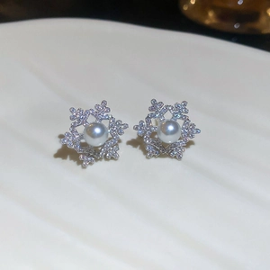Winter snowflake stud earrings featuring silver metal, sparkly crystals and a center pearl