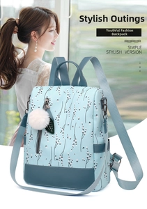 Détail d'un sac à dos bleu clair à fleurs avec pompon blanc et finitions en cuir gris