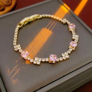 Detailed close-up of a luxury gold chain bracelet with square pink and white zircon stones