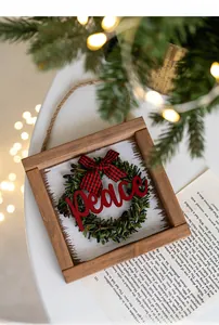 Close-up of wooden Christmas door sign with Peace text and red plaid bow decoration