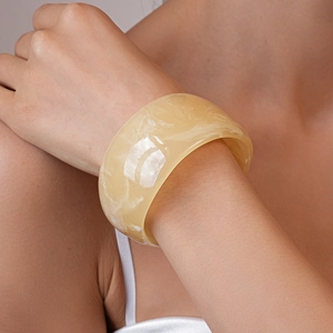 Close-up of wide marble resin bangle in creamy yellow with smooth polished finish