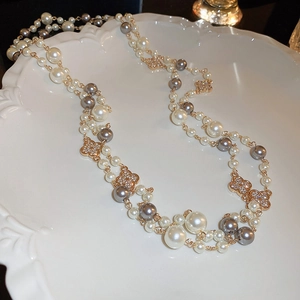 Macro detail of multi-layer gold plated pearl necklace with clover crystal elements