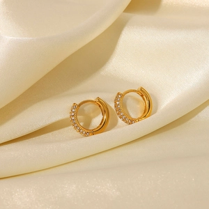 Close-up of 18K gold-plated hoop earrings with clear zircons on elegant silk fabric