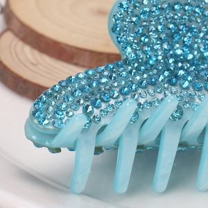 Detailed close-up showing blue acrylic hair claw clip with shimmering rhinestones