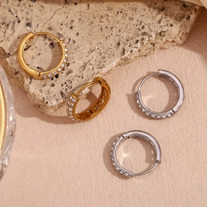 Detailed macro view of gold and silver hoop earrings with micro-set zircons on stone