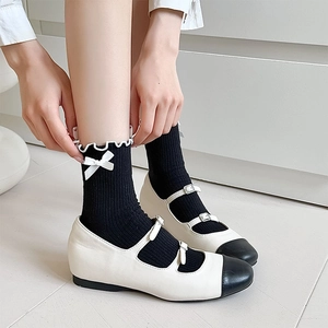 Close-up of black JK ruffle socks with white bow accents and Mary Jane shoes