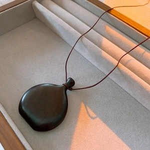 Macro shot of a vintage ebony wood money bag pendant necklace on a grey velvet display