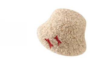 Détail d'un chapeau bob en polaire beige orné de nœuds rouges à pois et texture douce