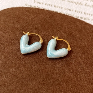 Gros plan de boucles d'oreilles cœur plaquées or avec émail marbré bleu clair