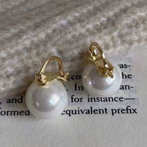 Detail of S925 sterling silver stamp on gold buckle pearl earrings with knit background