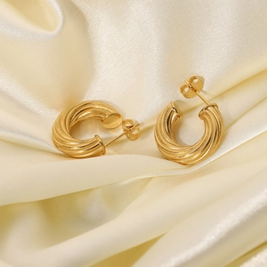 Detailed view of 18K gold plated twisted hoop earrings on luxury champagne silk fabric