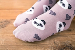 Detail view of cotton socks with purple heart and cute panda patterns on a wooden floor