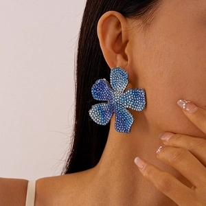 Detailed view of oversized flower earrings with blue gradient zircon crystals on model