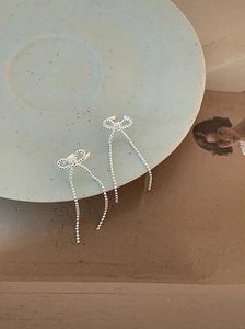 Detailed close-up of silver bow tassel earrings with sparkling bead chains
