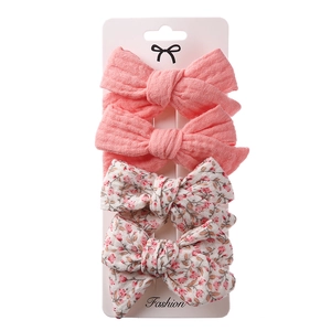 Detail of 4-piece bow hair clips set with floral and pink fabric textures on display card