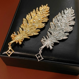 Close-up of gold and silver feather brooches with rhinestones on black leather base