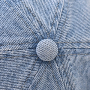 Macro shot of light blue washed denim baseball cap top with stitching details