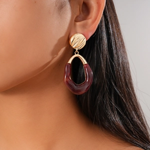 Detail of model wearing gold and burgundy resin geometric earrings in a vintage style