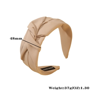 Detail of light brown fabric headband featuring a twisted knot design and handmade label