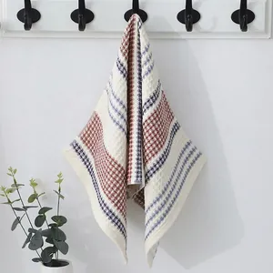 Detail of off-white waffle weave cotton towel with red and blue stripes on a wall hook