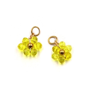 Macro shot of two yellow crystal flower charms with gold beads on a white background