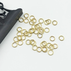 Golden open jump rings for DIY jewelry making laid on a white surface for crafts