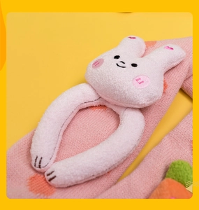 Close-up of a pink knitted scarf with a cute white plush 3D bunny decoration detail