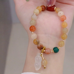 Close-up of colorful beaded bracelet with a white jade-like gourd pendant on wrist