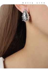 Macro view of teardrop-shaped titanium steel earrings with pearls and fine diamonds