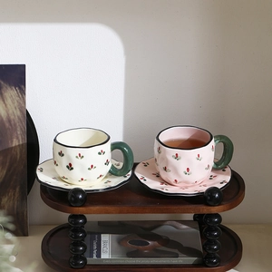 Detail of pink and cream irregular ceramic coffee cups with red floral patterns