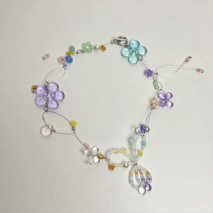 Macro shot of handmade beaded necklace with glass flower charms and bow detail