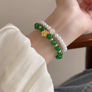 Detail of 2-piece layered bracelet with green glass beads, pearls, and gold flower charm
