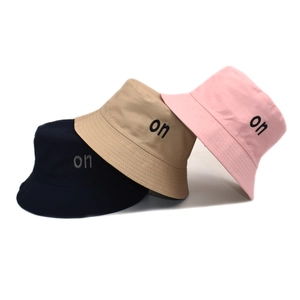 Three cotton bucket hats in navy, beige, and pink with 'on' embroidery on plain background