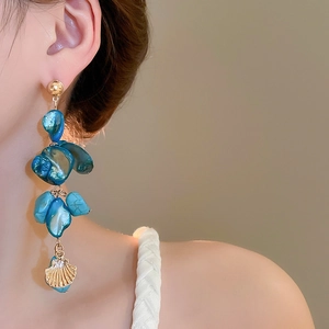 Detail of blue turquoise beaded earrings with gold metal and shell charms on model