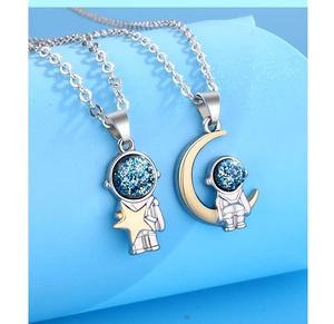 Macro shot of astronaut necklaces with blue glitter visors and gold-plated star and moon charms