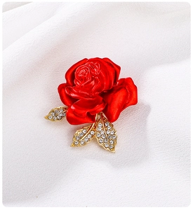 Macro shot of red enamel rose brooch with golden leaves and sparkling rhinestones